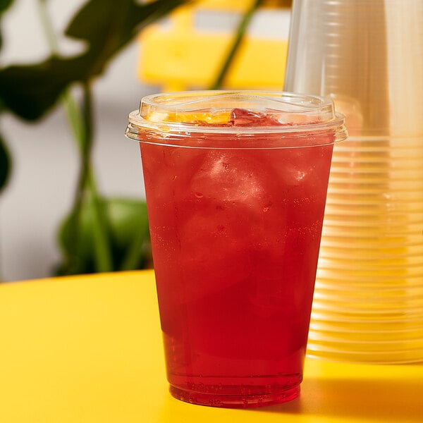 A plastic Tossware cup with a red drink and a Tossware natural plant-based plastic sip lid.
