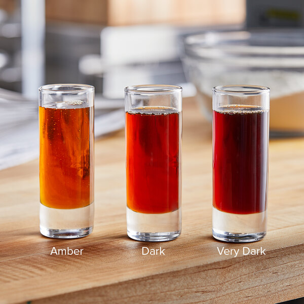 A group of glasses with different colored liquid on a table.
