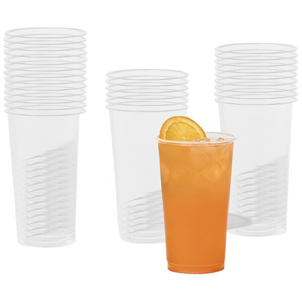 A Tossware plastic cup filled with orange juice with a slice of orange on the rim.
