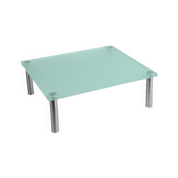 A Dalebrook clear green acrylic display riser on a glass table with metal legs.