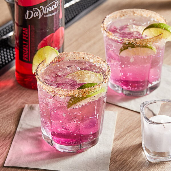 Two pink drinks with lime slices in them.