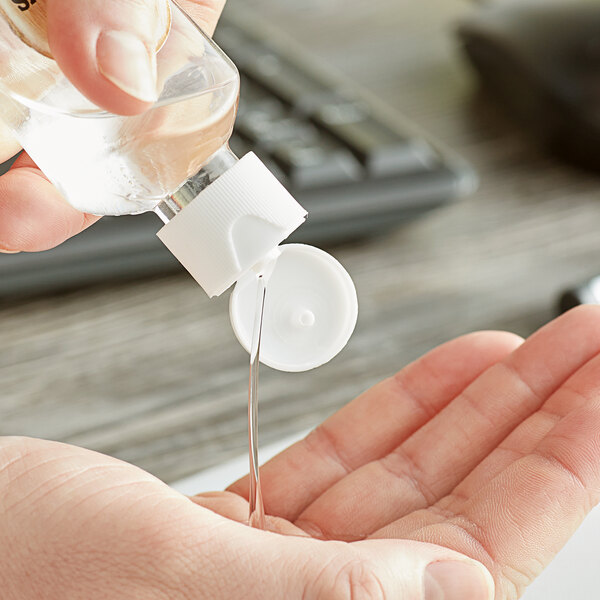 A hand pouring liquid into a white container using a white 20/410 flip top lid.