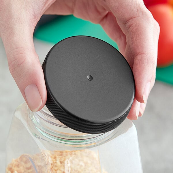 A hand holding a jar with a 63/400 black ribbed plastic cap with foam liner.