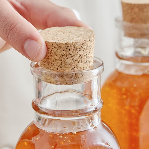 A person's hand corking a jar of honey.