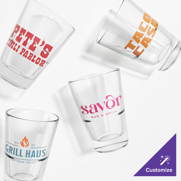 A group of Tossware Reserve stackable shot glasses with custom orange and pink text.