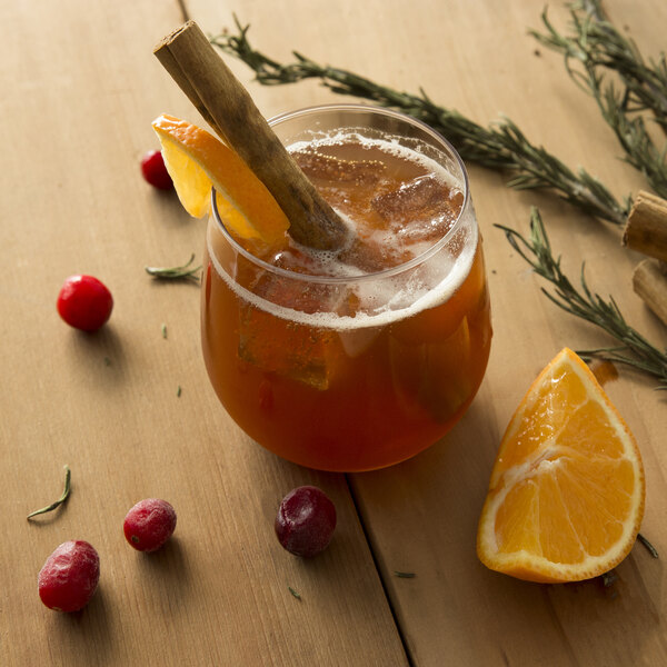 A Tossware plastic Vino XL glass of liquid with orange slices and a cinnamon stick.