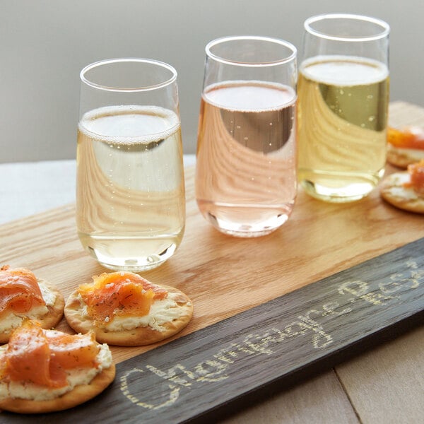 Tossware plastic champagne flutes filled with champagne on a table with crackers.