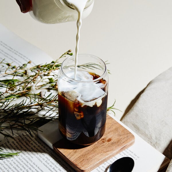 A Tossware plastic can glass filled with white liquid being poured into it.