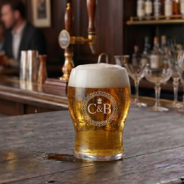 A customizable 4 oz. plastic taster glass filled with beer, placed on a wooden bar counter.