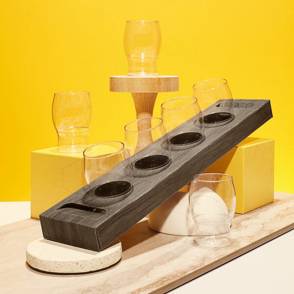 A Tossware cardboard tasting flight tray with 4 oz. glasses on a table.