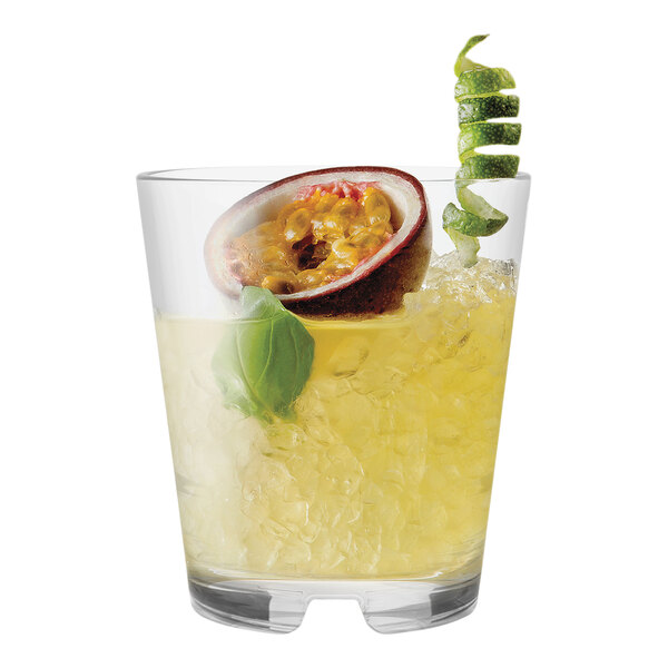 A Tossware plastic rocks glass with a drink and a slice of passion fruit on a table.