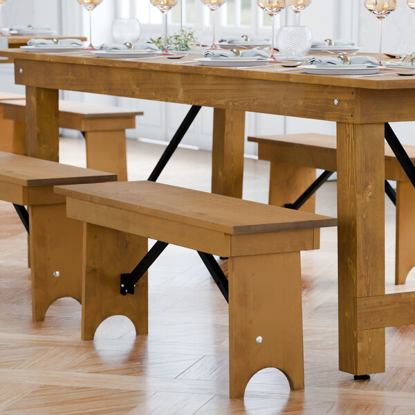 A Lancaster Table & Seating Vineyard Series wooden folding bench on a wood floor.