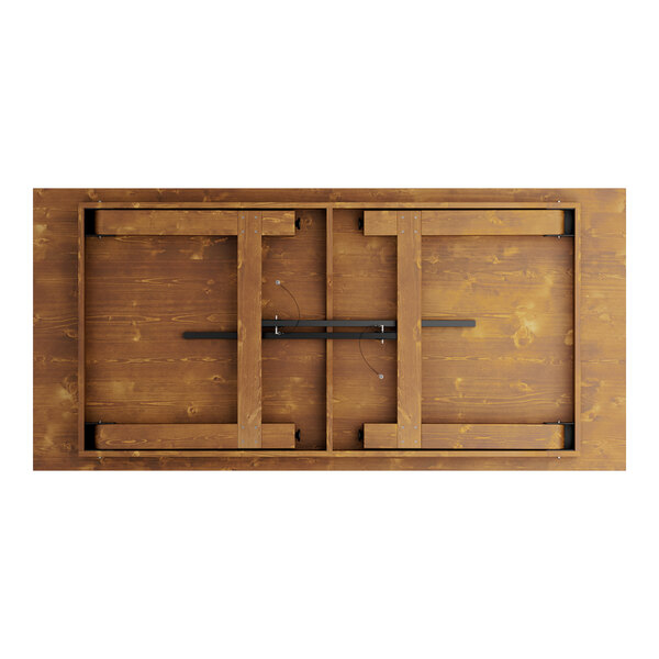 A Lancaster Table & Seating barrel brown outdoor folding table with wooden slats and black metal bars on the surface.