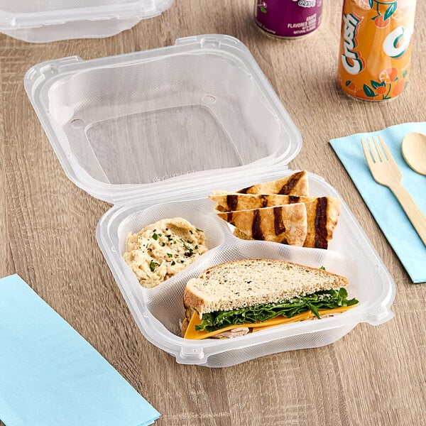 A Genpak clear plastic hinged container with a sandwich, lettuce, and cheese on a plate.