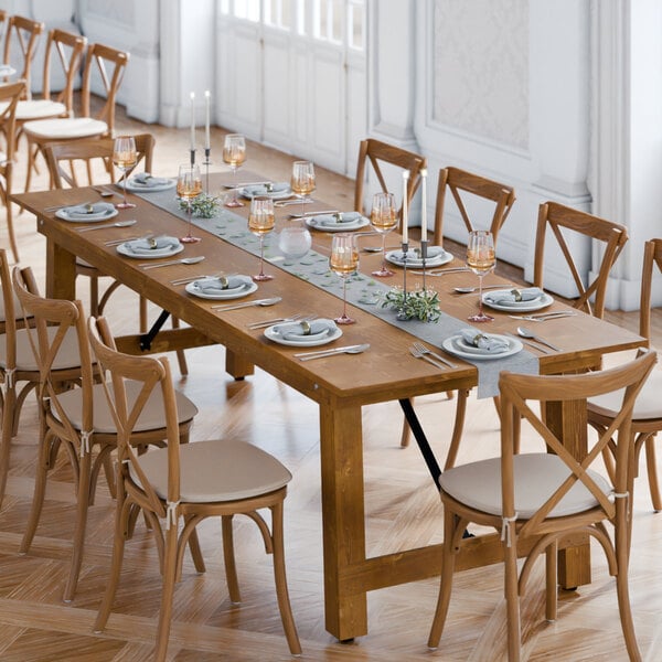 A Lancaster Table & Seating Vineyard Series barrel brown folding table with plates and wine glasses on it.