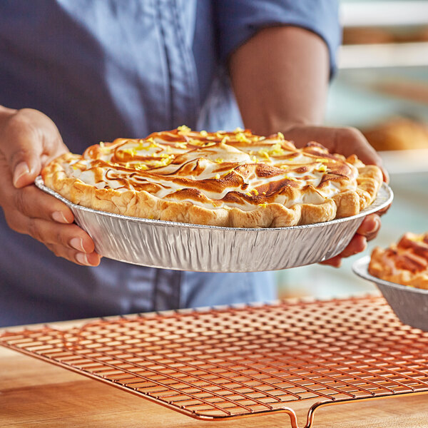 A person holding a Baker's Lane pie on a table.