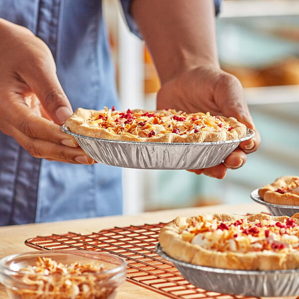 A person holding a pie in a Baker's Lane foil pie pan.