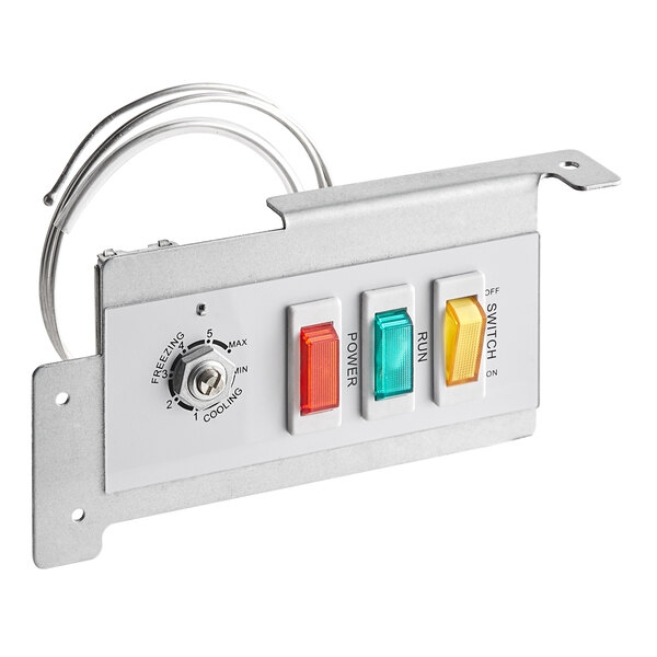 A metal panel with three switches and a light.