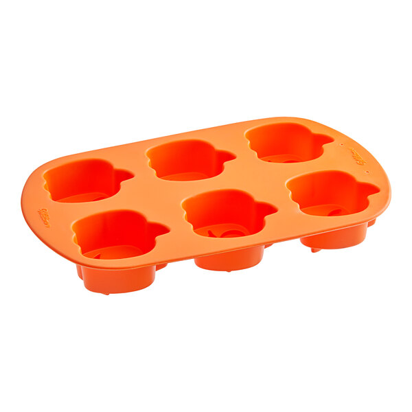 An orange silicone mold with six pumpkin-shaped compartments.