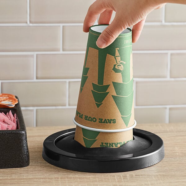 A hand using a KleanTake in-counter cup dispenser to get a paper cup with a lid.