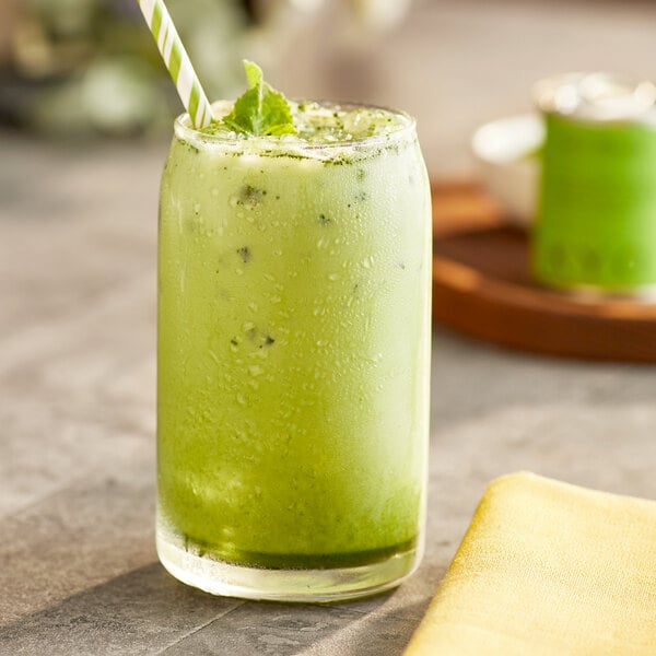 A glass of Dona Ceremonial Matcha with a straw in it.