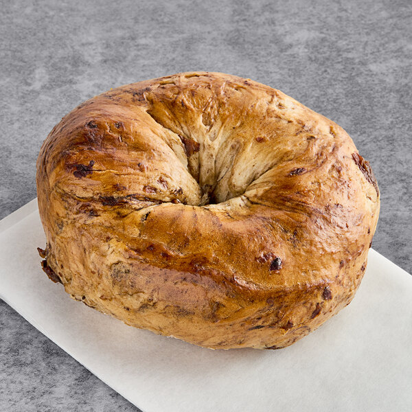 A Just Bagels cinnamon raisin bagel on a white surface.