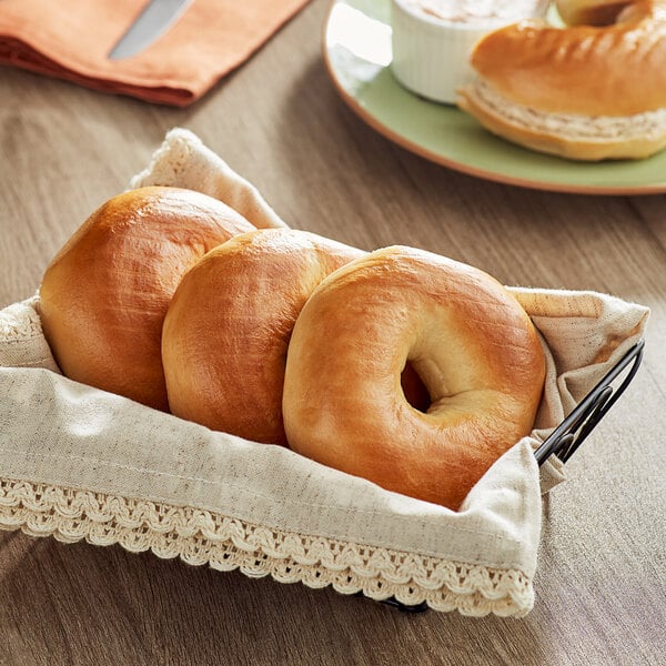 Just Bagels plain bagels in a basket on a table.