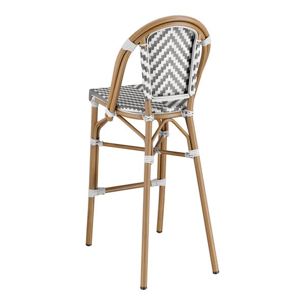 A Lancaster Table & Seating Bistro Series gray and white rattan barstool with a chevron weave and a wooden frame.