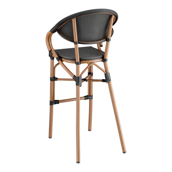 A Lancaster Table & Seating black Teslin arm barstool on a wooden frame with black cushions.