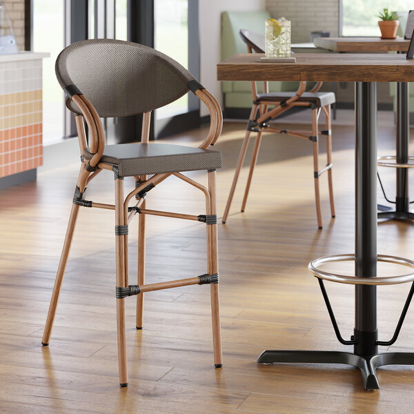 A brown outdoor arm barstool with a curved back and woven seat, designed for bistro or patio use.