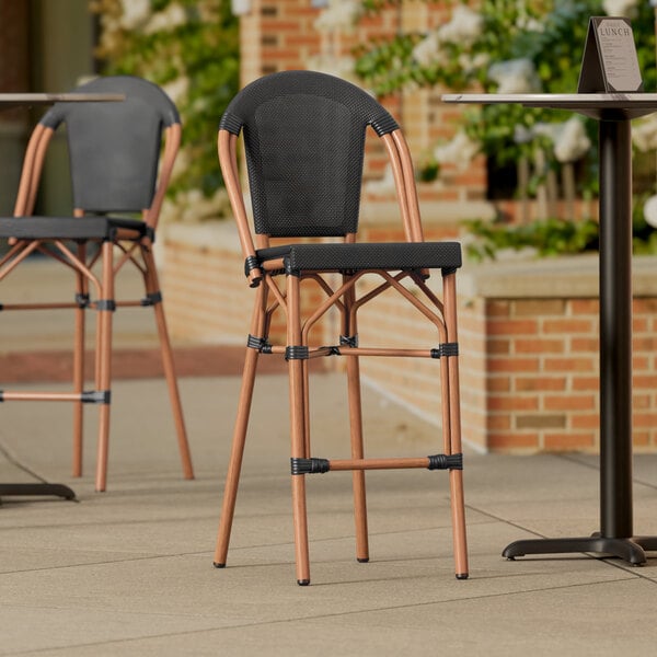 Two Lancaster Table & Seating black outdoor barstools on a patio.