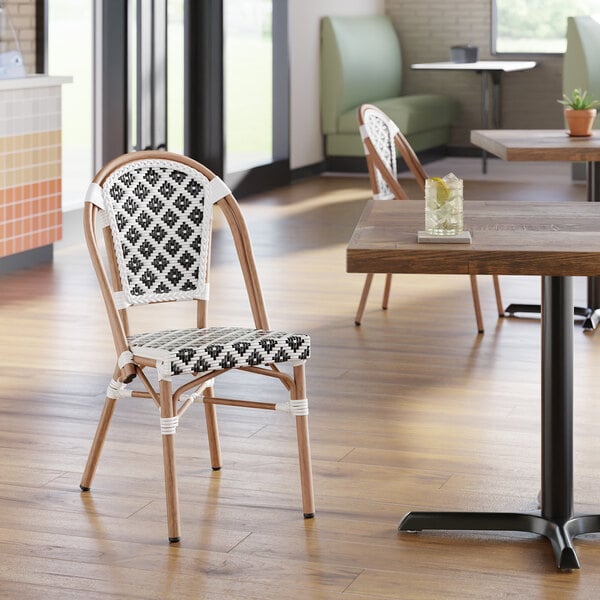 A black and white birdseye weave rattan outdoor side chair with a curved back and wooden frame.