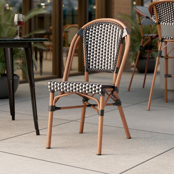 A Lancaster Table & Seating black and white checkered rattan chair on an outdoor patio.