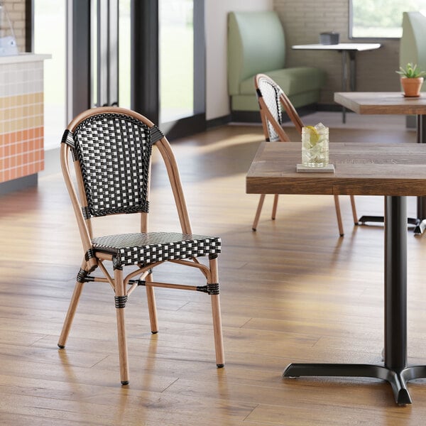 A black and white checkered weave rattan outdoor side chair with a curved back and light brown frame.