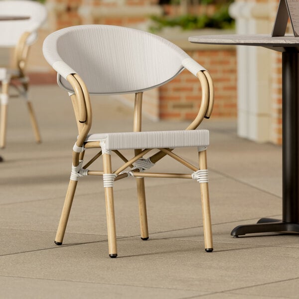 A Lancaster Table & Seating gray Teslin outdoor arm chair on a patio.