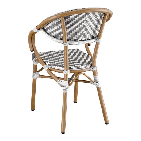 A Lancaster Table & Seating Bistro Series rattan arm chair with a gray and white chevron weave seat back.