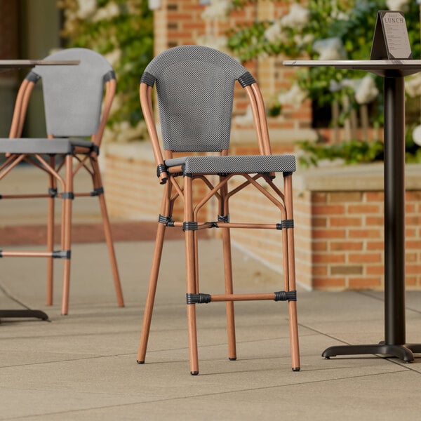 A Lancaster Table & Seating black and white outdoor barstool on a patio.