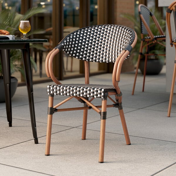 A Lancaster Table & Seating black and white rattan outdoor chair on a patio.