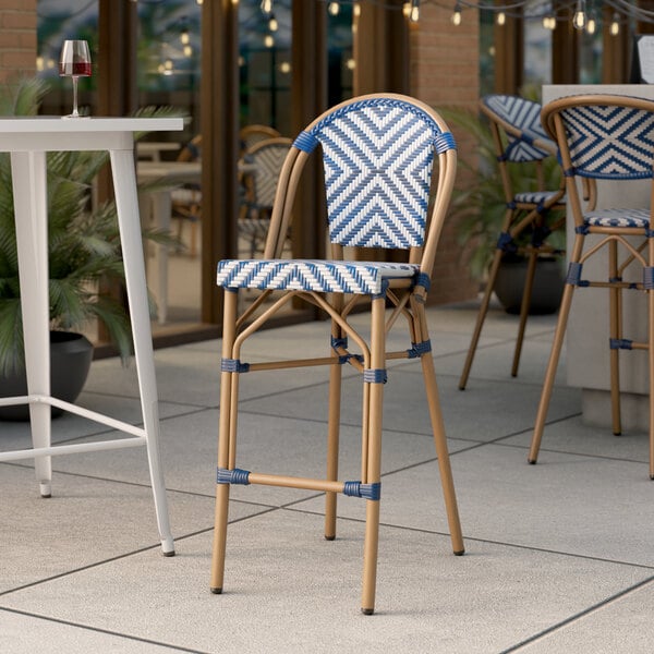 A Lancaster Table & Seating navy and white chevron weave rattan barstool on an outdoor patio.