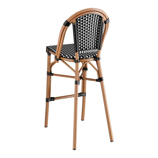 A Lancaster Table & Seating black and white checkered weave rattan bar stool.