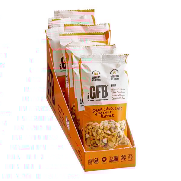A pack of The GFB Dark Chocolate Peanut Butter Bites in 1.2 oz bags, displayed in an orange box containing 10 packs.