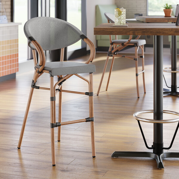 A black and white outdoor arm barstool with a curved back and wooden legs.