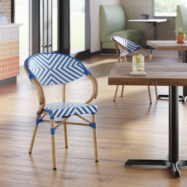 A navy and white chevron weave rattan outdoor arm chair with a curved back and wooden legs.