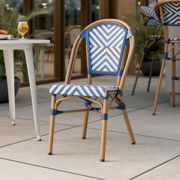 A blue and white Lancaster Table & Seating Bistro Series rattan outdoor chair on a patio.