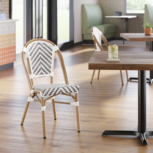 A gray and white chevron weave rattan outdoor side chair with a curved back and light wood frame.