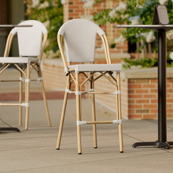 A group of Lancaster Table & Seating Bistro Series outdoor side barstools with gray seats on a brick patio.