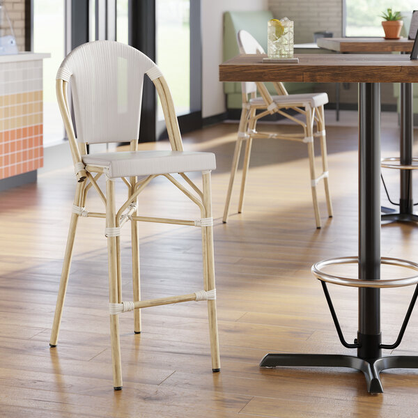 A light-colored outdoor side barstool with a woven seat and backrest, featuring a bistro-style design.