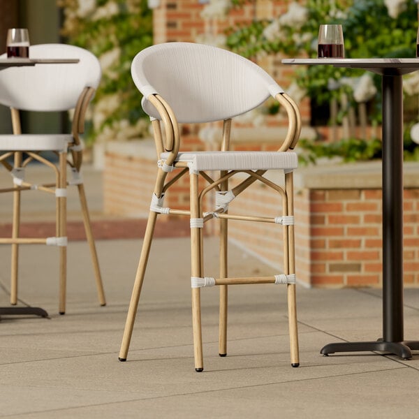 A Lancaster Table & Seating outdoor arm barstool with a gray seat on a table outside.