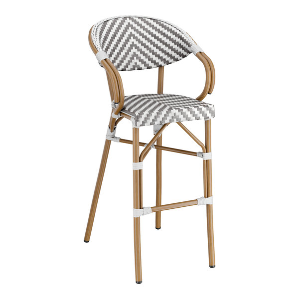 A Lancaster Table & Seating outdoor rattan barstool with a gray and white checkered seat.
