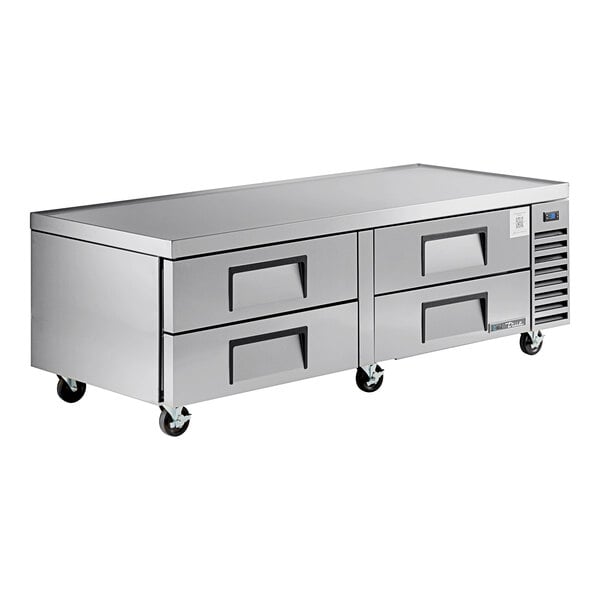 A stainless steel refrigerated chef base with four drawers and caster wheels.